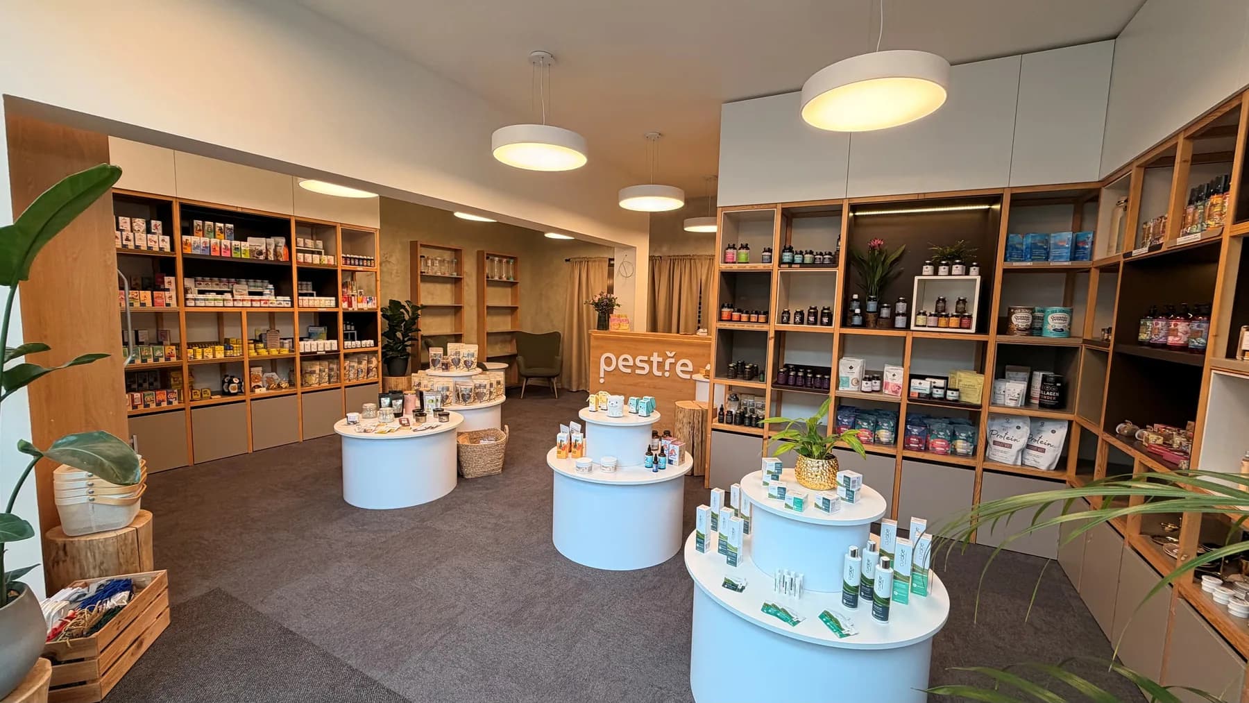 Prodejna pestře po rekonstrukci — regály podél stěn a kulaté stolky s produkty uprostřed